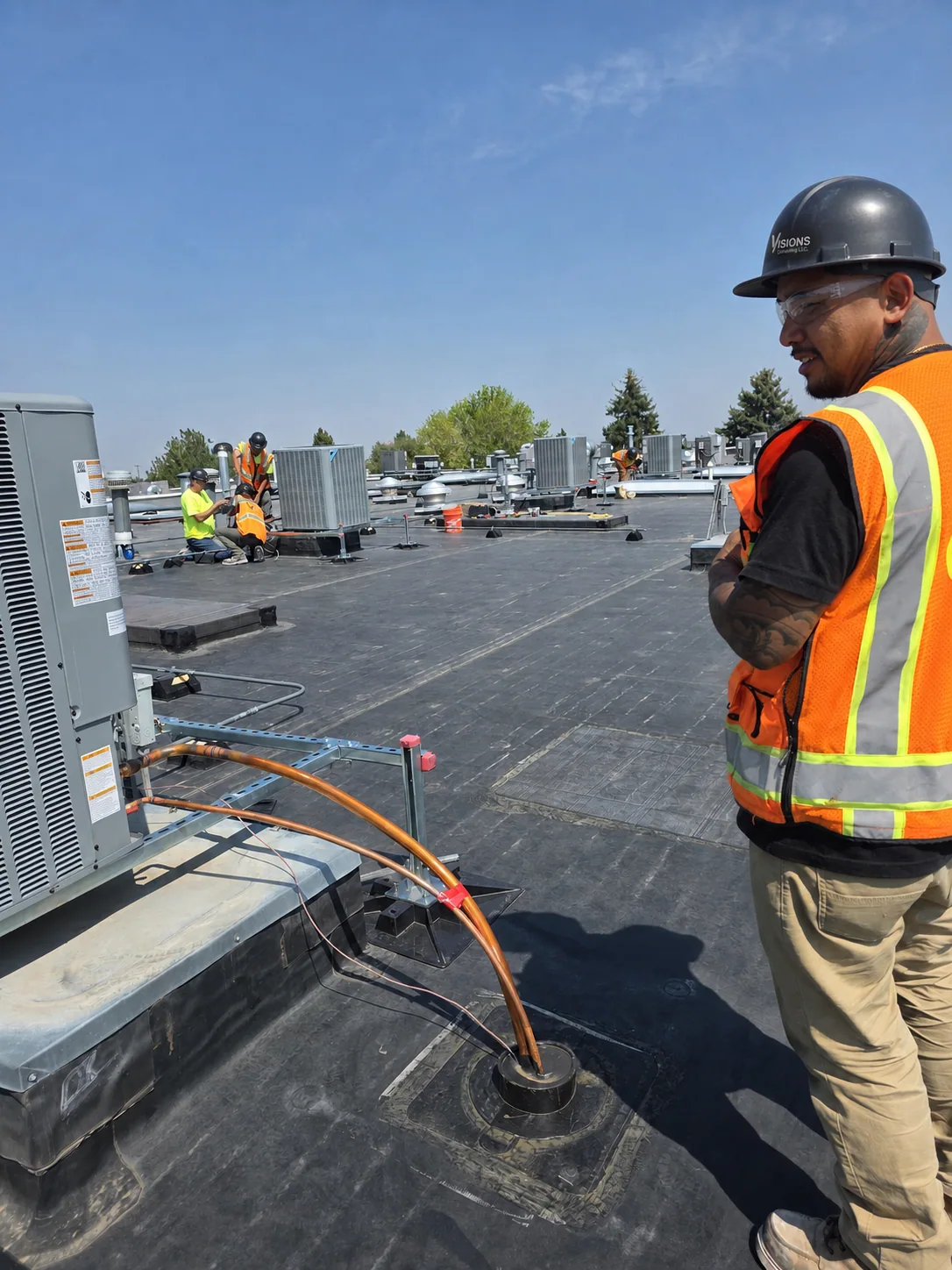 Visions employees coordinating rooftop equipment work in proper PPE
